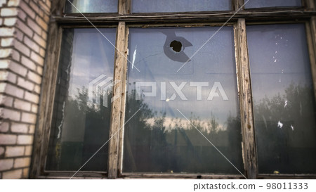 hole in the window pane of an old house. Glass broken by hooligans with a stone 98011333