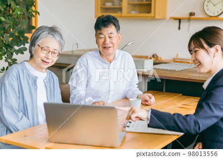 A business woman in a suit explaining to an Asian elderly couple on a personal computer A business woman in a suit explaining to an Asian elderly couple on a personal computer 98013556