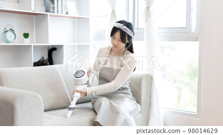 Woman vacuuming the floor of her living room, Big cleaning in the house, Removes germs and dirt and deep stains, Housewife cleaning, Keeping her home clean, Domestic hygiene. Woman vacuuming the floor of her living room, Big cleaning in the house, Removes germs and dirt and deep stains, Housewife cleaning, Keeping her home clean, Domestic hygiene. 98014629