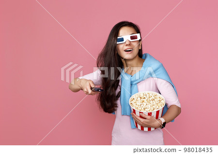 woman in 3d glasses with remote control holding bucket of popcorn woman in 3d glasses with remote control holding bucket of popcorn 98018435