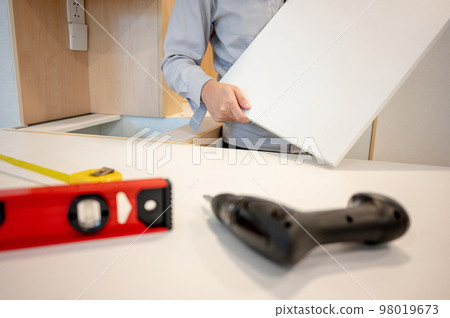 Male furniture assembler installing cabinet panel Male furniture assembler installing cabinet panel 98019673