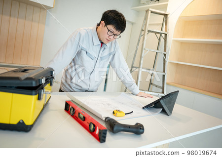 Asian male Interior worker working with architectural drawing Asian male Interior worker working with architectural drawing 98019674
