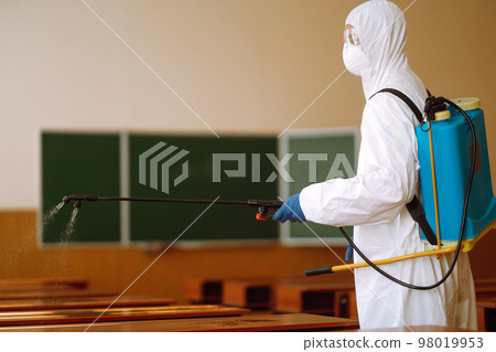 Disinfecting of office to prevent COVID-19, Man in protective hazmat suit with with spray chemicals. Disinfecting of office to prevent COVID-19, Man in protective hazmat suit with with spray chemicals. 98019953