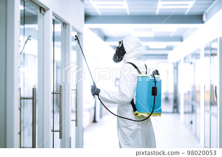 Disinfecting of office to prevent COVID-19, Man in protective hazmat suit with spray chemicals. Disinfecting of office to prevent COVID-19, Man in protective hazmat suit with spray chemicals. 98020053