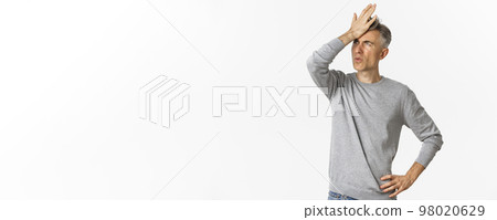 Image of frustrated and distressed middle-aged man, making facepalm and exhaling disappointed, standing over white background 98020629