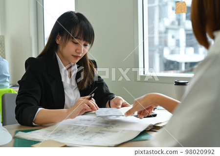 Architect team working together on design of a construction plan and examining construction plans at co working space 98020992
