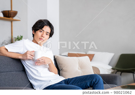 Young man relaxing in the living room Young man relaxing in the living room 98021062