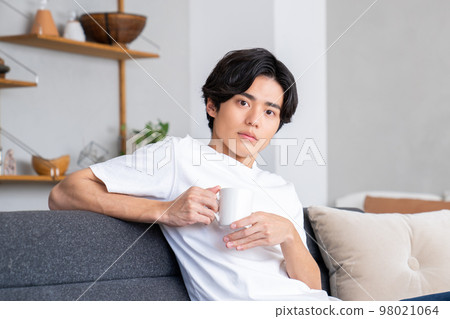 Young man relaxing in the living room 98021064