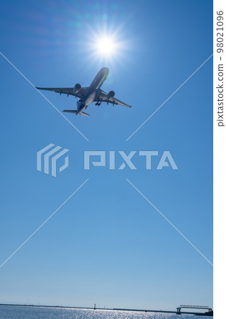 Passenger plane heading to the airport flying in the clear sky 98021096