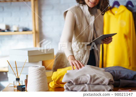 Small business owner, entrepreneur, seller using tablet checking ecommerce clothing store orders. 98021147