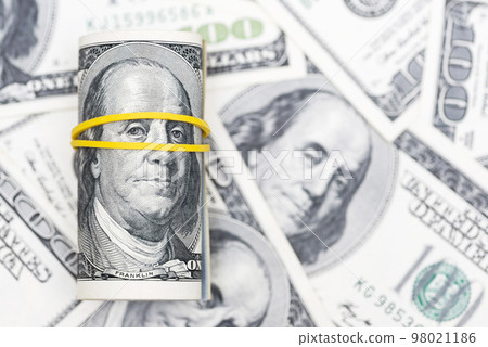 A roll of 100 dollar bills closeup on pile of American dollars. Background 98021186