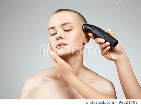 haircut of a beautiful girl. pretty woman cutting hair with hairclipper 98021409
