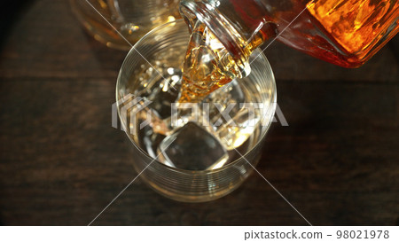 Pouring whisky into the glass, macro shot. Pouring whisky into the glass, macro shot. 98021978
