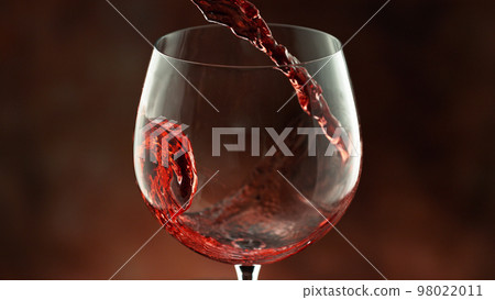 Pouring red wine into the glass, macro shot. Pouring red wine into the glass, macro shot. 98022011