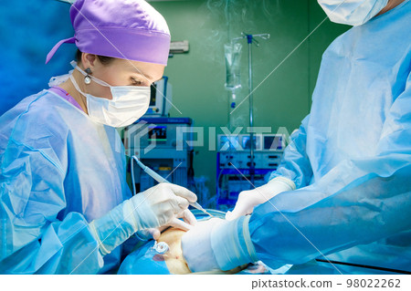A female surgeon with an electric coagulator operates on a patient. A female surgeon with an electric coagulator operates on a patient. 98022262