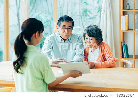 Care manager explaining to senior couple 98022594