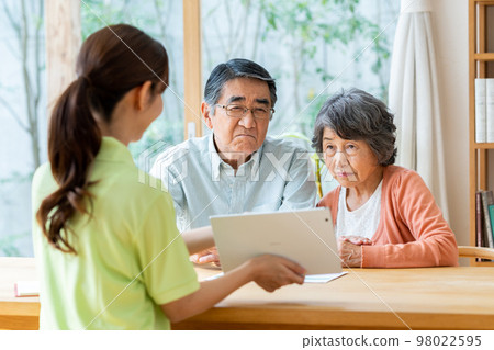 Care manager explaining to senior couple 98022595