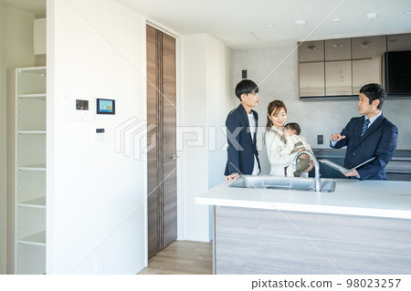 Private viewing: A young couple with a baby looking at the kitchen of a newly built apartment 98023257
