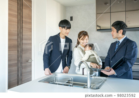 Private viewing: A young couple with a baby looking at the kitchen of a newly built apartment 98023592