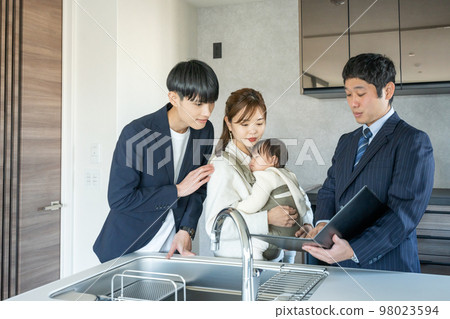 Private viewing: A young couple with a baby looking at the kitchen of a newly built apartment 98023594