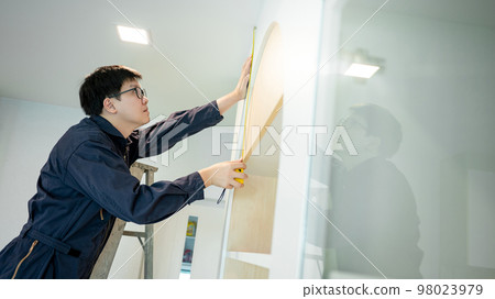 Asian male furniture assembler using tape measure Asian male furniture assembler using tape measure 98023979