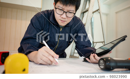 Asian male Interior worker working with architectural drawing 98023990