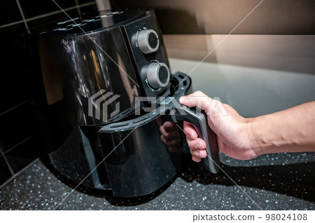 Male hand holding an electric air fryer handle 98024108