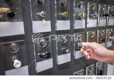 Male hand choosing cabinet door knob in furniture store Male hand choosing cabinet door knob in furniture store 98024110
