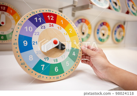 Male hand holding colorful wooden clock Male hand holding colorful wooden clock 98024118