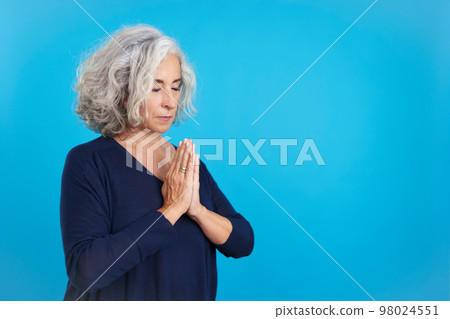 Mature woman praying with folded hands and closed eyes 98024551