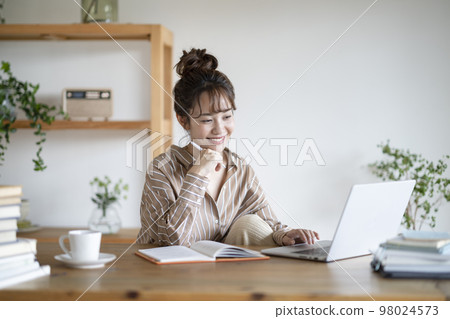 Smiling young woman looking at laptop screen 98024573