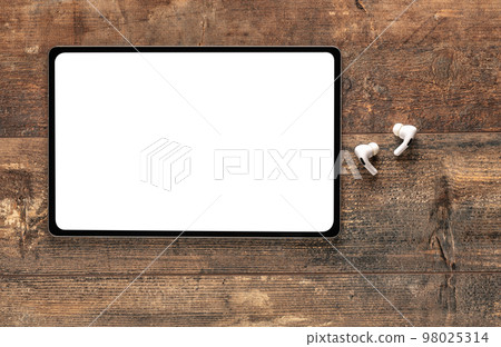 Mockup digital tablet. top view of blank white screen tablet, wireless earphone on old rustic wooden table. Top view blank screen tablet Mockup digital tablet. top view of blank white screen tablet, wireless earphone on old rustic wooden table. Top view blank screen tablet 98025314
