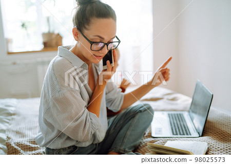 Young mother talking on the phone and discussing work issues while looking after her child. Covid-19. Young mother talking on the phone and discussing work issues while looking after her child. Covid-19. 98025573