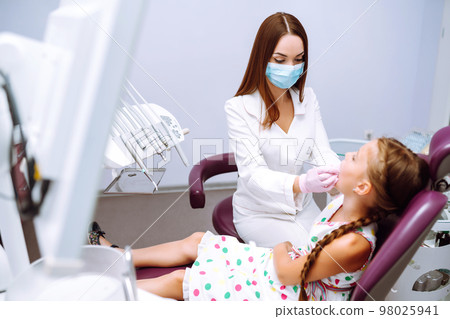 Lovely little girl smiling after doing examination in a pediatric stomatology. Milk teeth care. 98025941