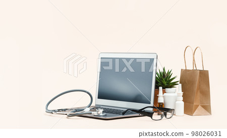Online pharmacy. prescription drugs and over the counter medication ready for delivery to customers. spray containers and buff paper bags near mockup laptop screen. Online consultations 98026031