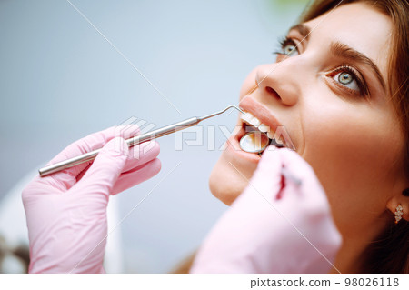 Young woman at the dentist's chair during a dental procedure. Overview of dental caries prevention. 98026118