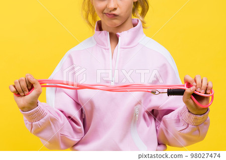 Adorable female child with skipping rope jumping in studio Adorable female child with skipping rope jumping in studio 98027474