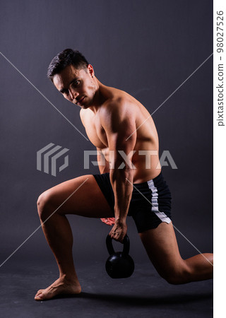 Handsome muscular man holding kettle bell with copy space. Hispanic male athlete 98027526