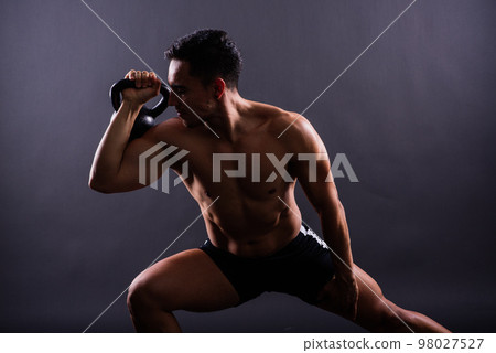 Handsome muscular man holding kettle bell with copy space. Hispanic male athlete 98027527