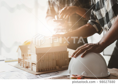 Architecture team drawing something while working with blueprint in the office. Architecture and Engineer concept Architecture team drawing something while working with blueprint in the office. Architecture and Engineer concept 98027880