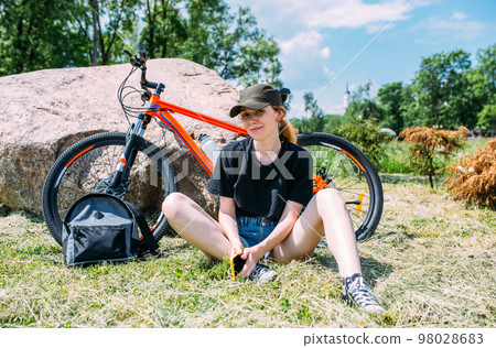 Young attractive woman is resting after bicycle ride. Active lifestyle, sports Young attractive woman is resting after bicycle ride. Active lifestyle, sports 98028683