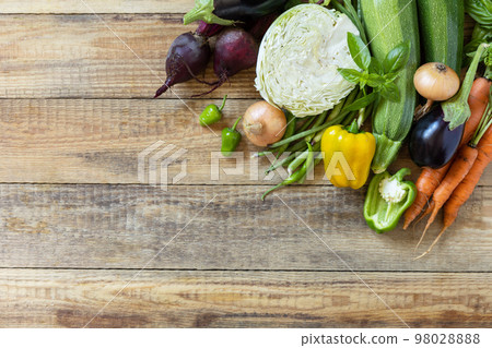 Organic vegetables for healthy cooking background. Fall harvest. The concept of vegan or diet food. Various vegetables on a rustic kitchen table. View from above. Organic vegetables for healthy cooking background. Fall harvest. The concept of vegan or diet food. Various vegetables on a rustic kitchen table. View from above. 98028888