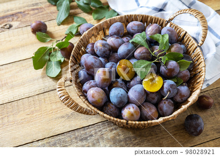 Fruit background, organic fruits. Still life food. Basket of fresh blue plums on a rustic wooden table. Copy space. 98028921
