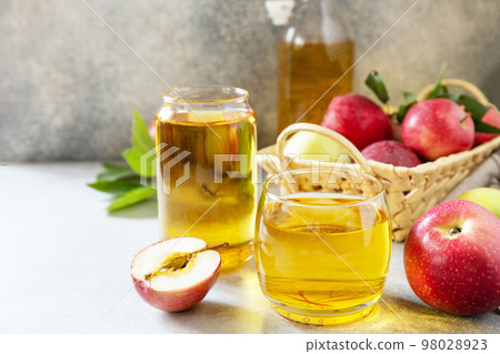 Autumn vitamin drink juice apple. Apple juice in a glass and fresh apples on a stone tabetop. Copy space. 98028923