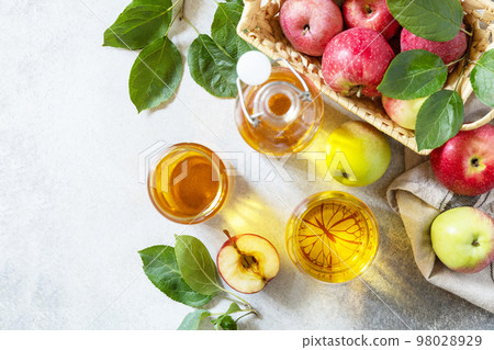 Apple juice in a glass and fresh apples on a stone tabetop. Autumn vitamin drink juice apple. View from above. Copy space. Apple juice in a glass and fresh apples on a stone tabetop. Autumn vitamin drink juice apple. View from above. Copy space. 98028929