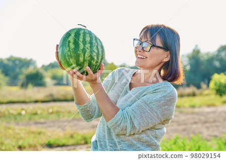 Smiling woman with ripe watermelon outdoor Smiling woman with ripe watermelon outdoor 98029154