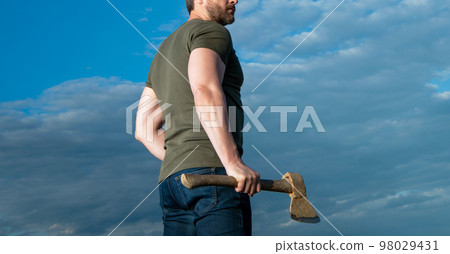cropped view of man with axe. lumberjack man hold ax. brutal man on sky background 98029431
