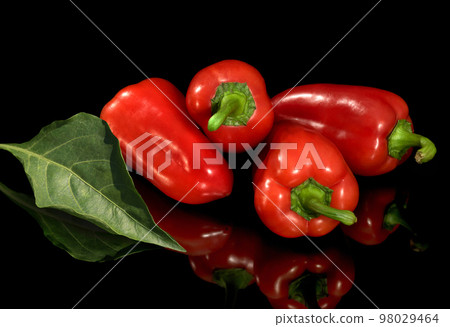 Bright fresh red pepper, is isolated on a black background Bright fresh red pepper, is isolated on a black background 98029464