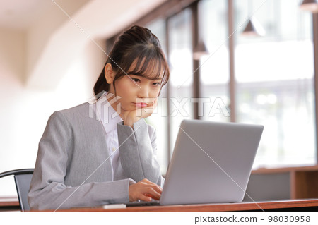 Desk work_Woman who stares at the PC with an angry face with a cheek cane_1 Desk work_Woman who stares at the PC with an angry face with a cheek cane_1 98030958