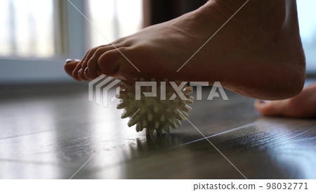Close-up, a woman doing a foot massage with a special massage ball. The concept of prevention and treatment of flat feet. Close-up, a woman doing a foot massage with a special massage ball. The concept of prevention and treatment of flat feet. 98032771